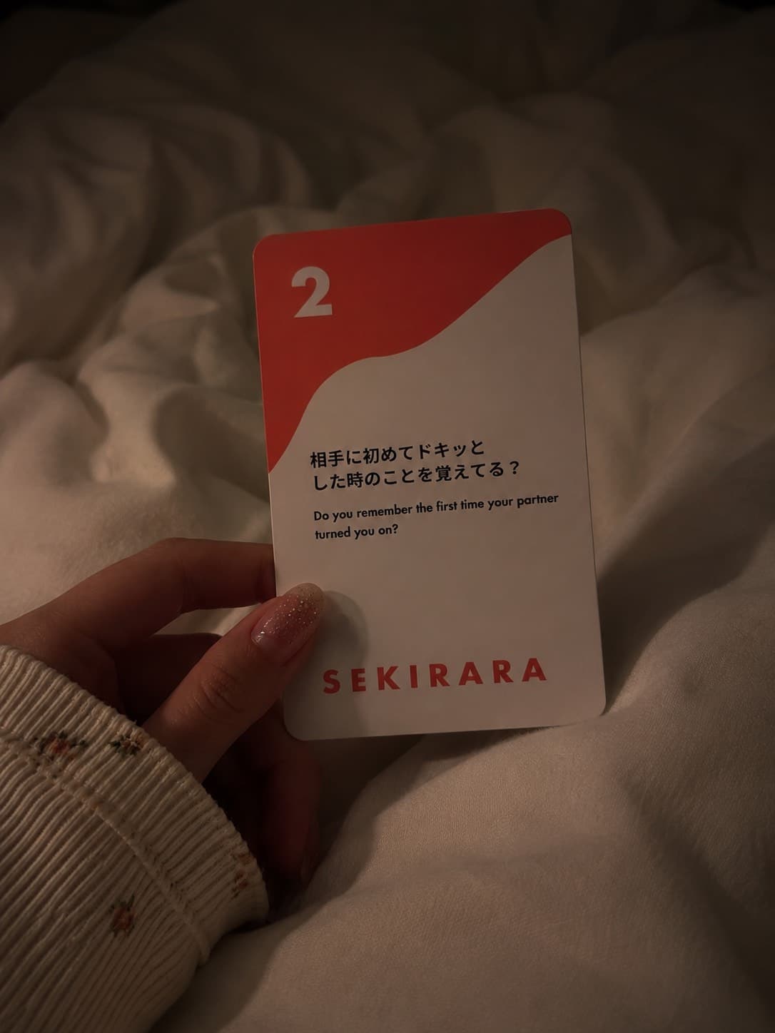 A hand holding card number 2 on a hotel bed