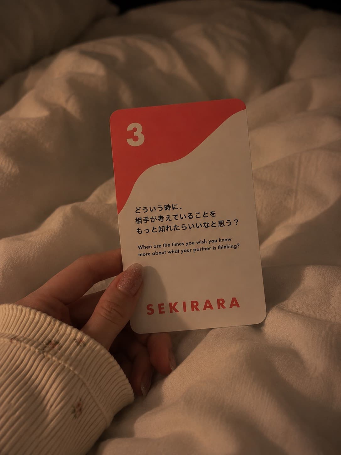 A hand holding card number 3 on a hotel bed