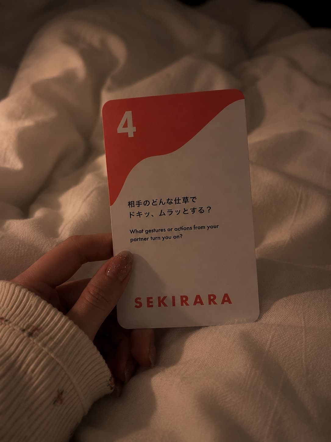 A hand holding card number 4 on a hotel bed
